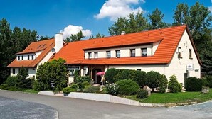 A two-story building with a red-tiled roof, a covered porch, and a well-maintained garden.