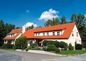 A two-story building with a red-tiled roof, a covered porch, and a well-maintained garden.