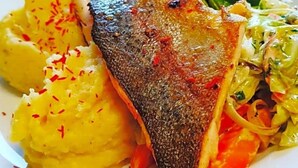 A plate of food with fish, potatoes, and greens.