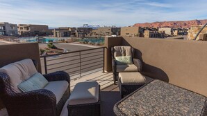 Una terraza en la azotea con mobiliario de mimbre, piscina y vistas a las montañas.