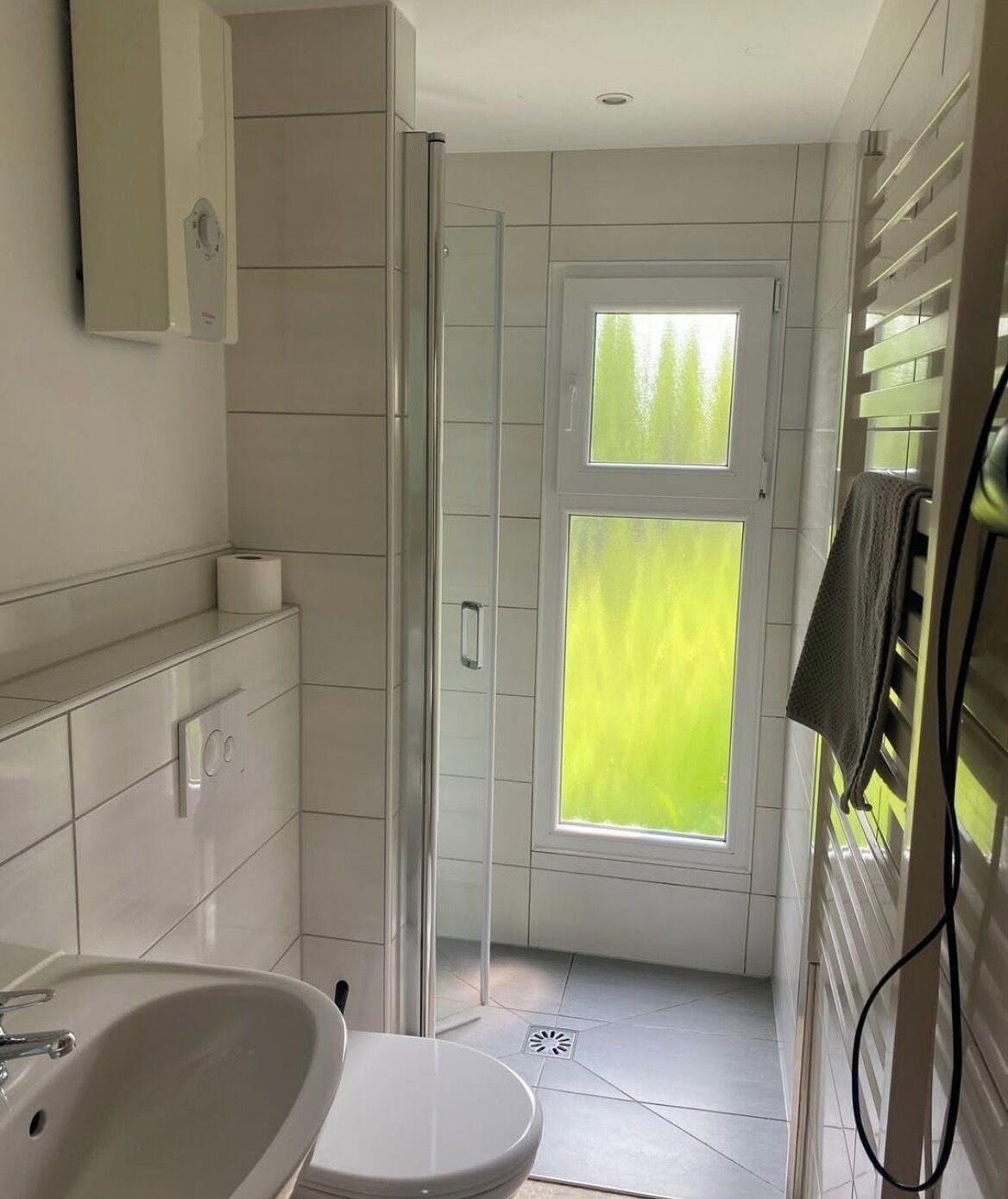 A modern bathroom with a shower, toilet, and sink.