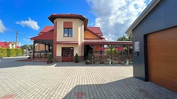 Ein zweistöckiges Haus mit rotem Dach, einer Laube und einer gepflasterten Auffahrt.