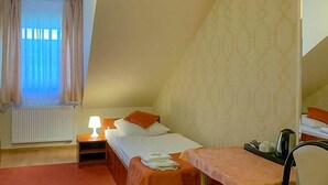 A bedroom with a bed, bedside table, lamp, and a small table with a chair.
