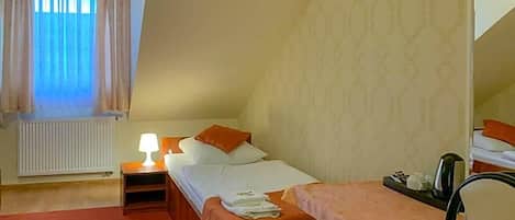 A bedroom with a bed, bedside table, lamp, and a small table with a chair.