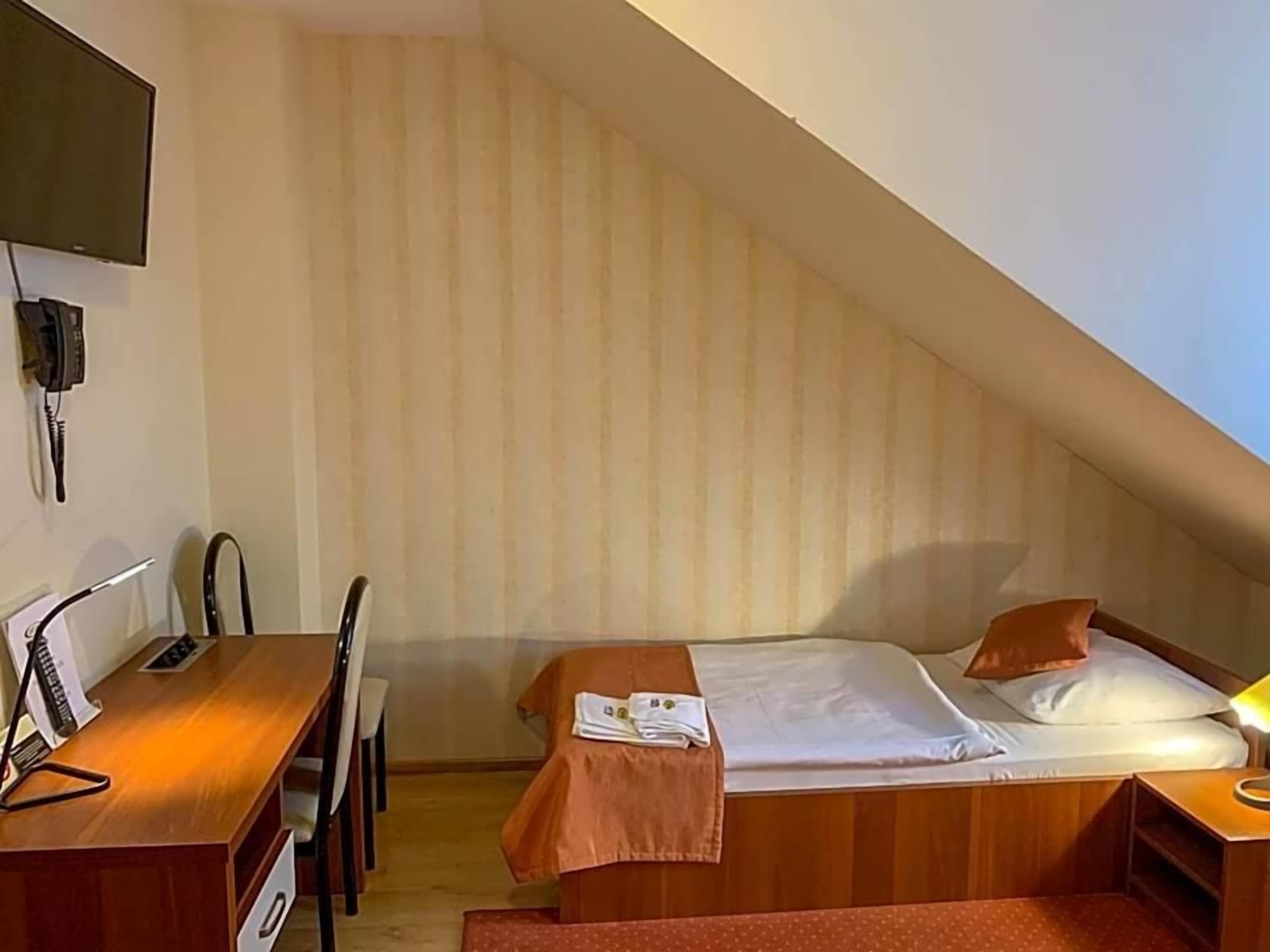 Una habitación de hotel pequeña y sencilla con escritorio, silla y dos camas.