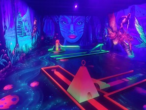 An indoor space with a futuristic design, including a central platform with a neon-lit structure and a large, illuminated face on the wall. - Ferienhaus Kristall, right in St. Englmar - with "Bavarian Forest" in the garden!  (Sankt Englmar)