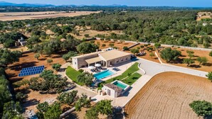 Vista aérea de una propiedad con una gran piscina, un edificio de piedra y paneles solares.