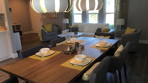 A dining area with a long wooden table set for four, surrounded by modern chairs.