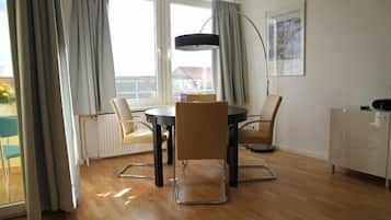 Ein moderner Essbereich mit einem runden Tisch, vier Stühlen und einer Pendelleuchte.
