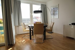 Een moderne eethoek met een ronde tafel, vier stoelen en een hanglamp.
