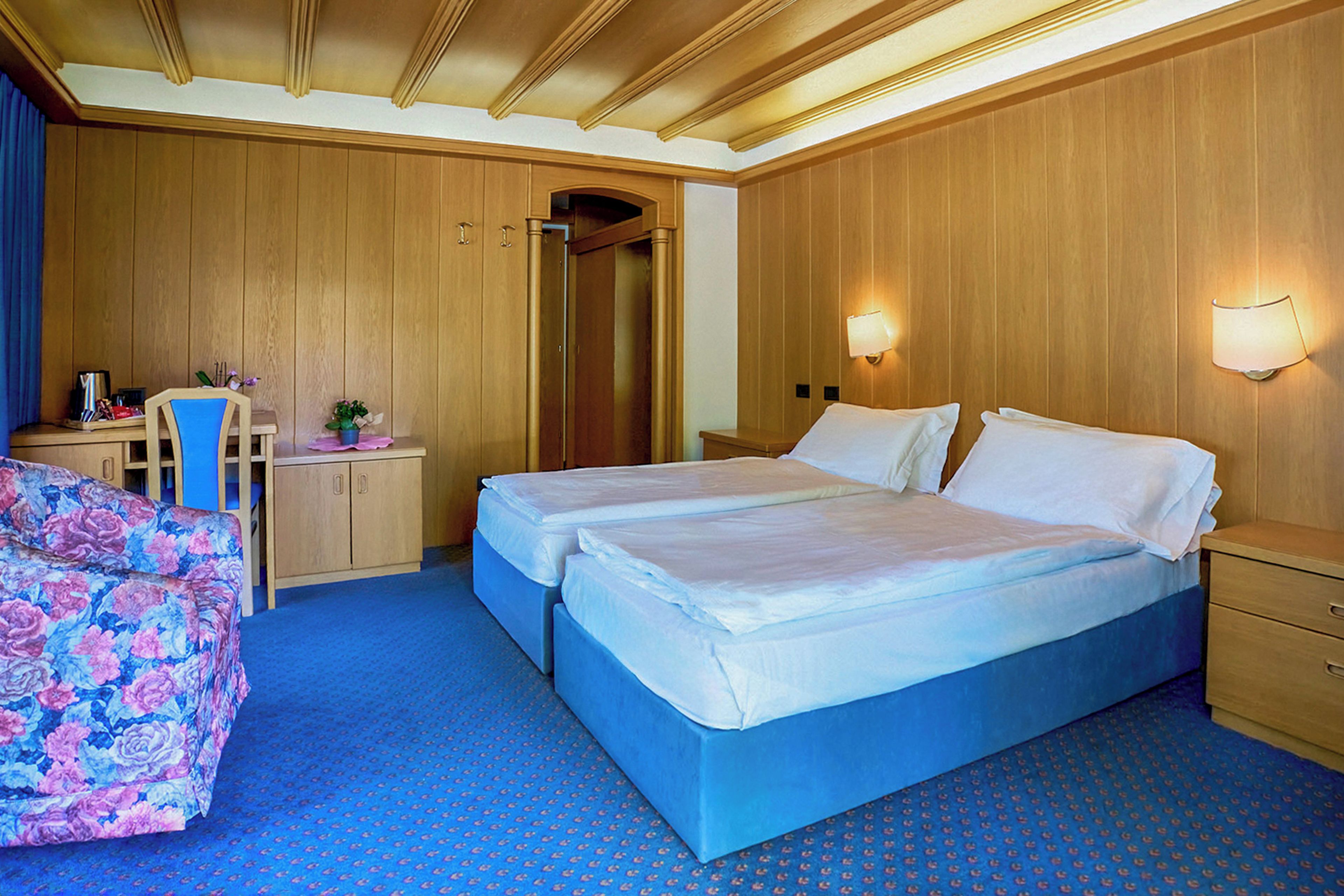 Una habitación de hotel con dos camas, un escritorio, una silla y un armario.