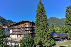 Un immeuble en bois à plusieurs étages, doté de balcons, entouré d’arbres et de montagnes.