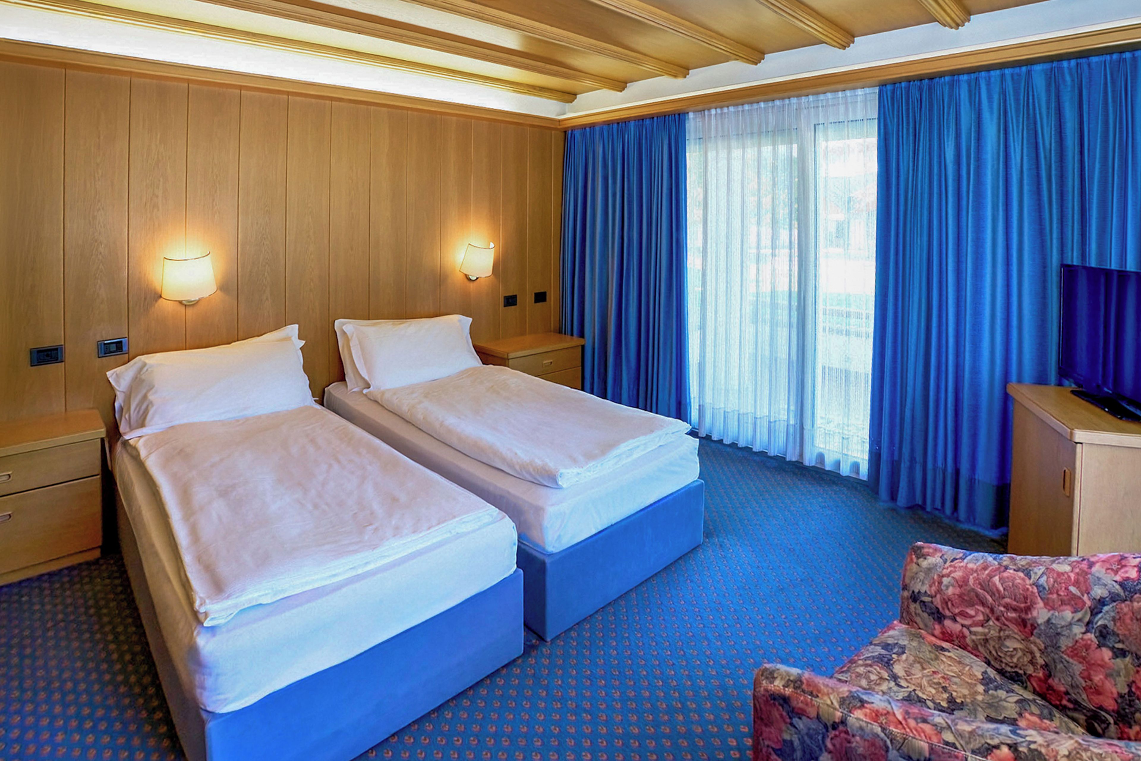 A hotel room with two beds, a desk, and a television.