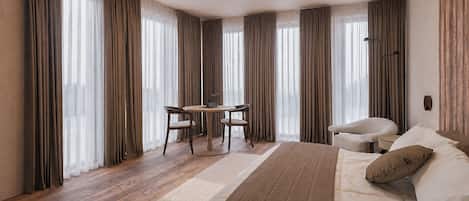 A hotel room with a bed, a desk with a chair, and a sofa.