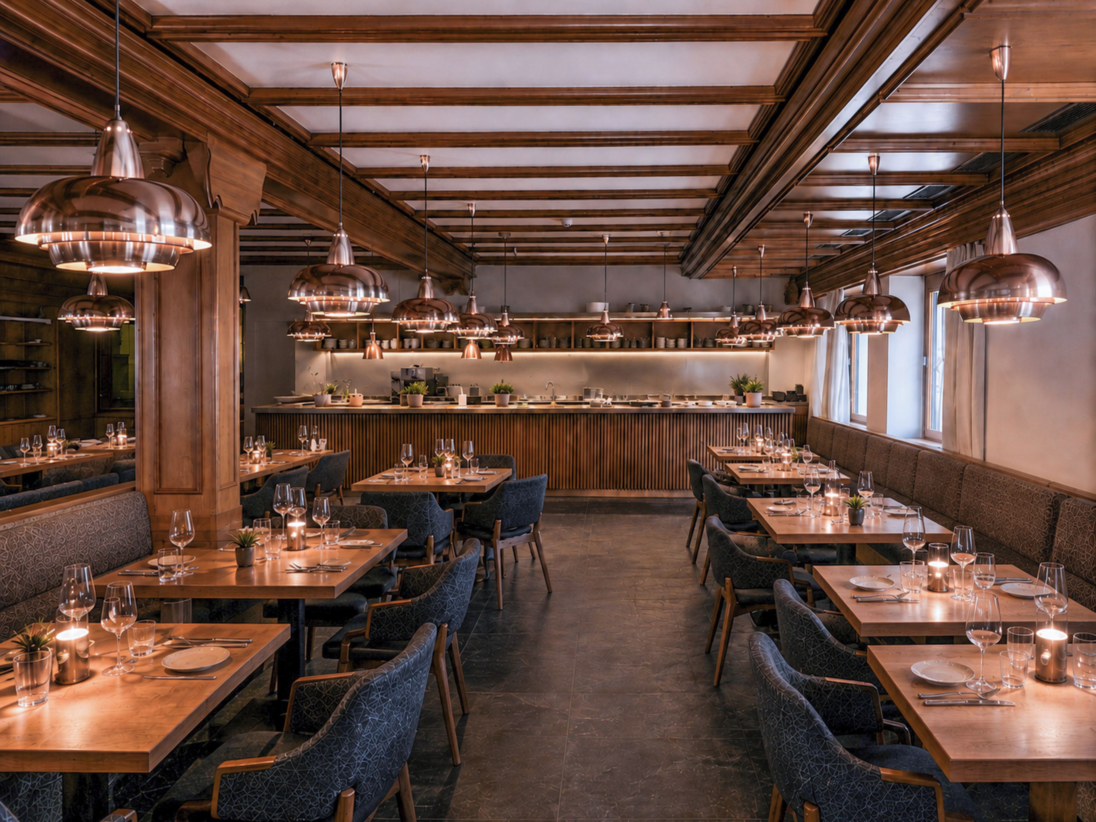 Un interno ristorante con diversi tavoli, sedie, luci a sospensione e un’area bar.