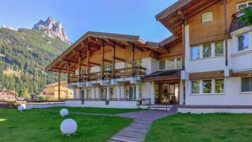 Un hôtel moderne avec une façade en bois, de grandes fenêtres et une vue sur la montagne.