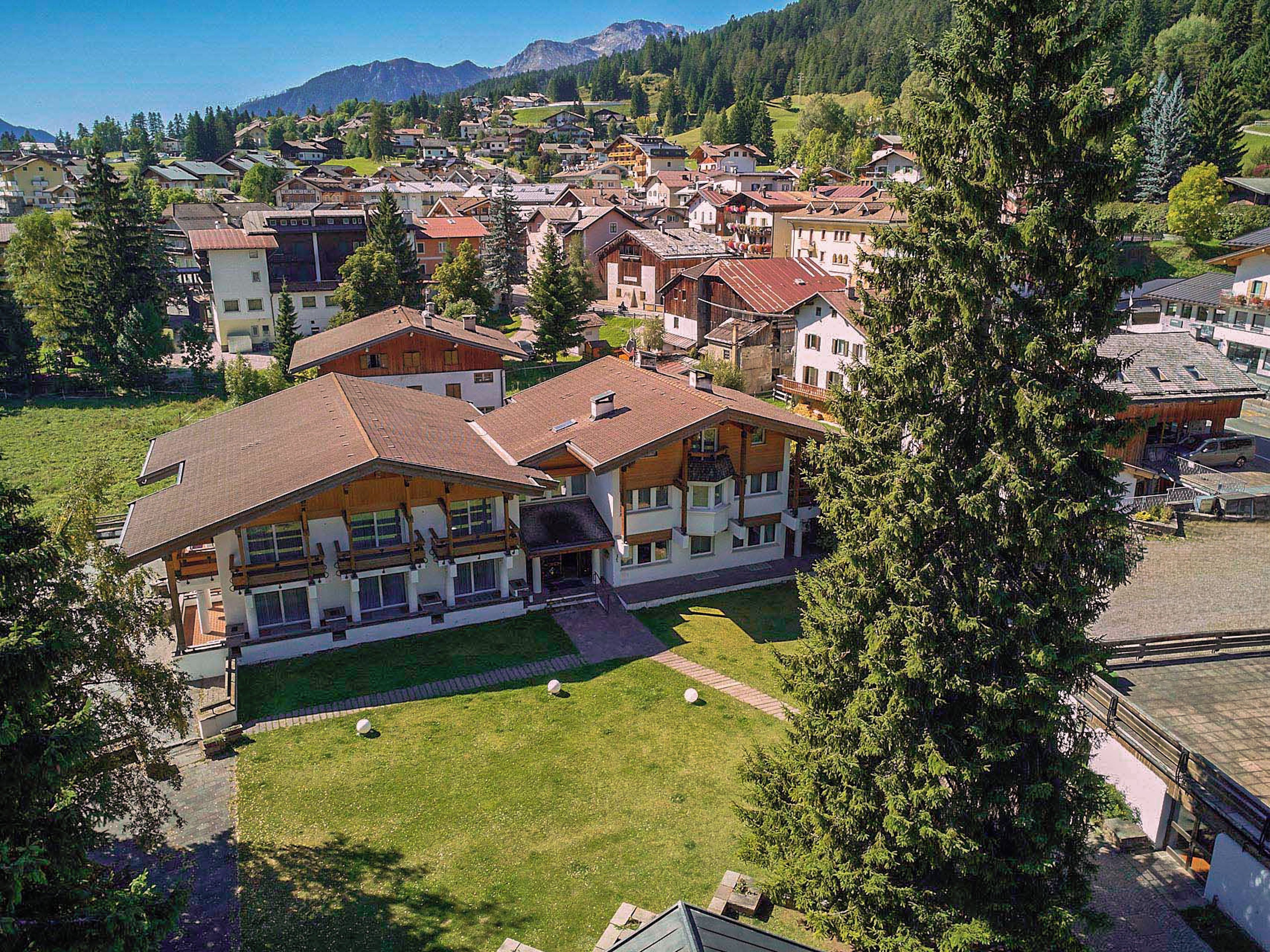 Un quartiere residenziale con diverse case, un edificio grande con tetto spiovente e un albero imponente.