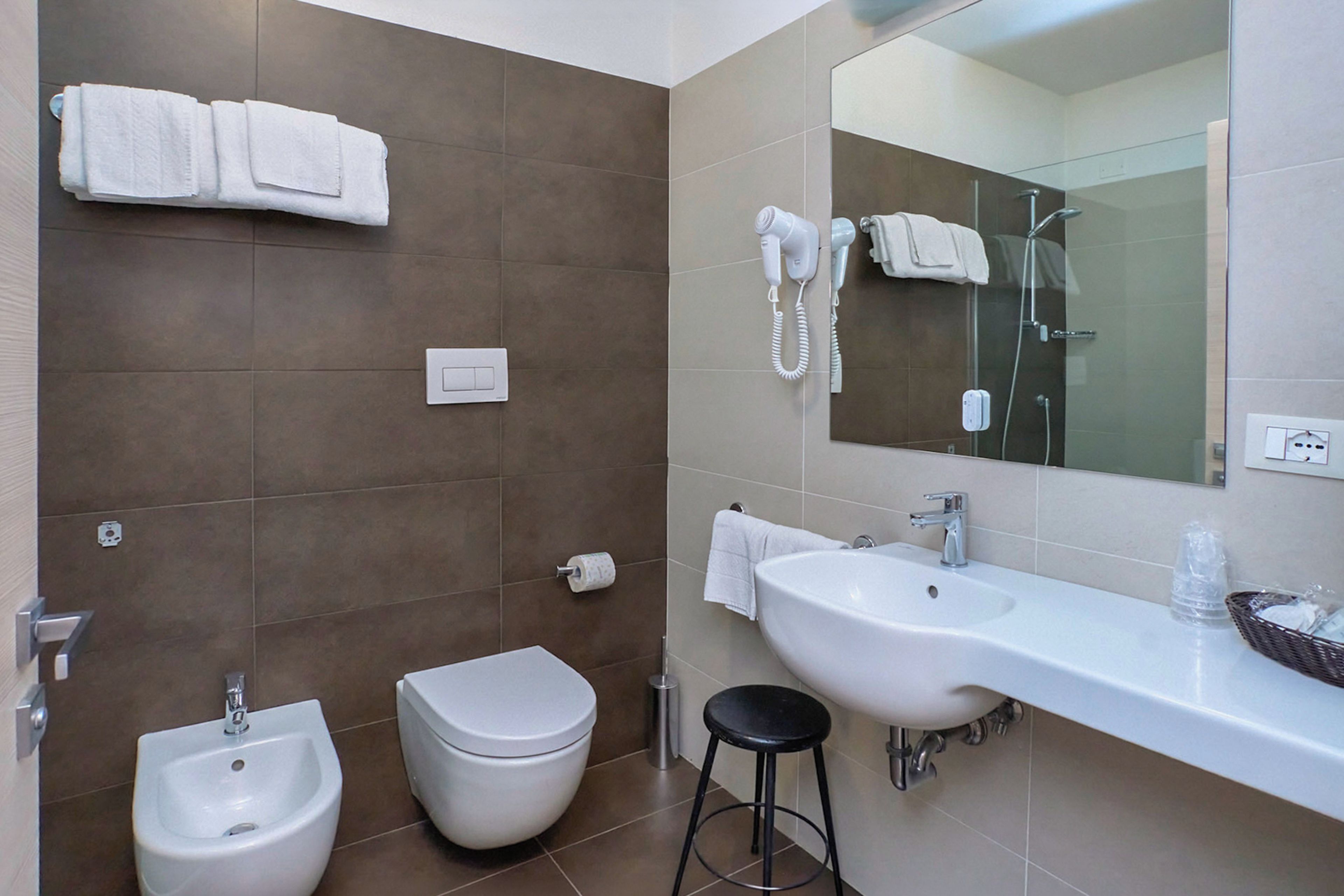 A modern bathroom with a bidet, toilet, sink, and a mirror.