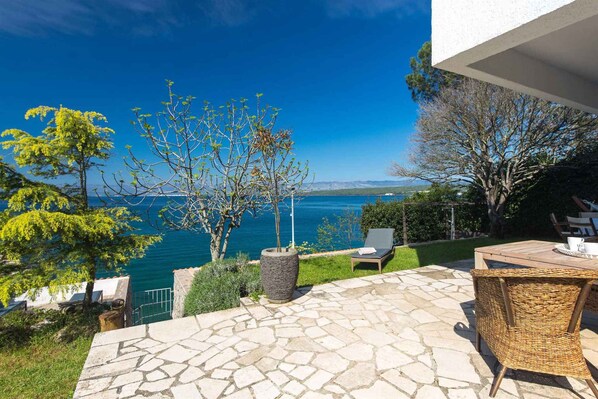 A patio with stone flooring, outdoor furniture, and a view of a body of water.