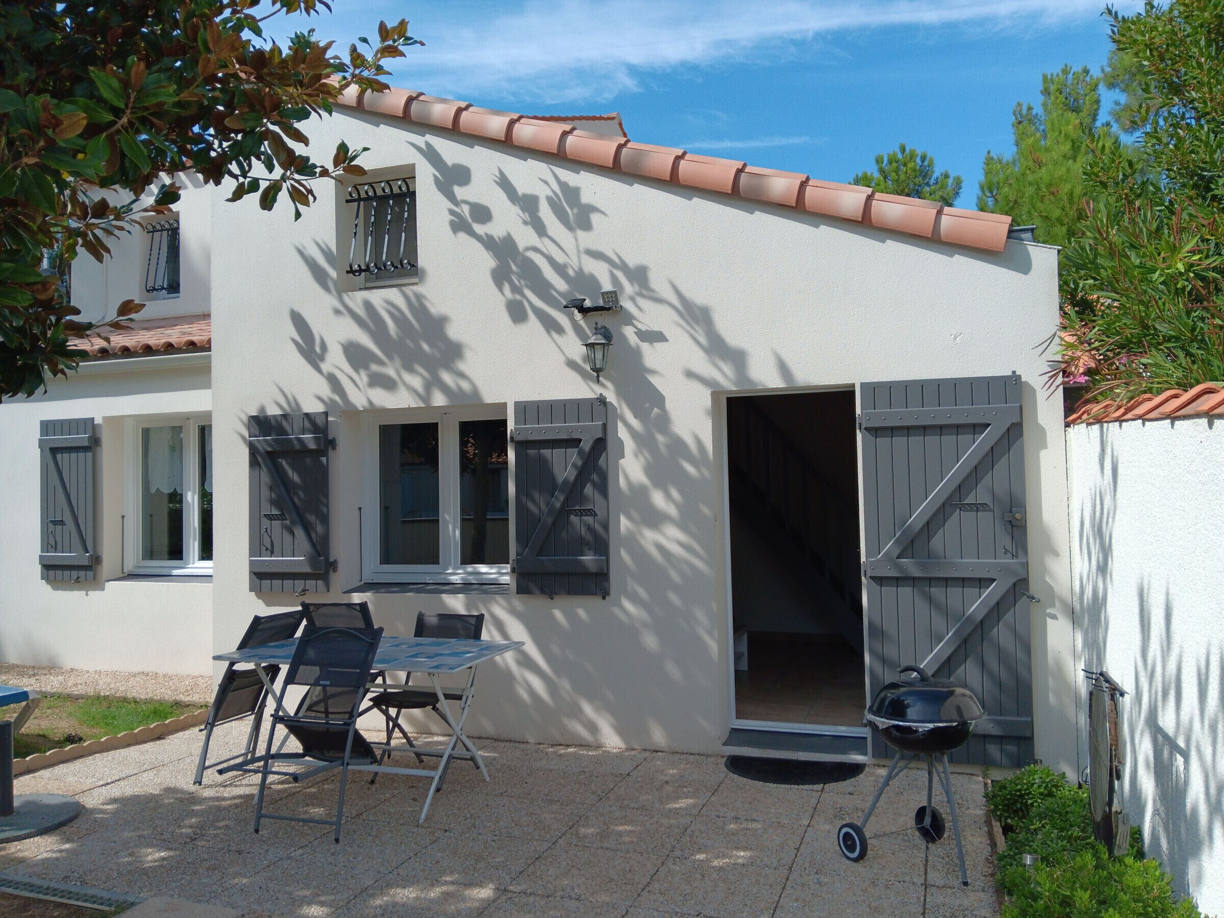 A white building with a tiled roof, a door, and a window with shutters.