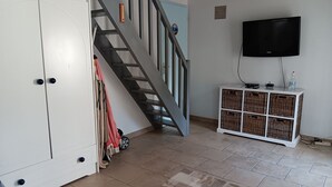 A living room with a staircase, a television mounted on the wall, and a white cabinet with wicker baskets. - Quiet cottage for 4 in La Faute-sur-Mer (La Faute-sur-Mer)