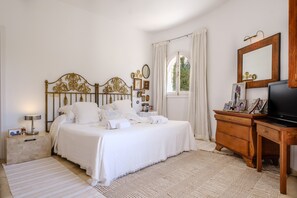 A bedroom with a bed, bedside tables, a dresser, a television, and a window with curtains. - Fantastic Holiday Home with Sea View, Pool, Terrace (Can Furnet, Ibiza)