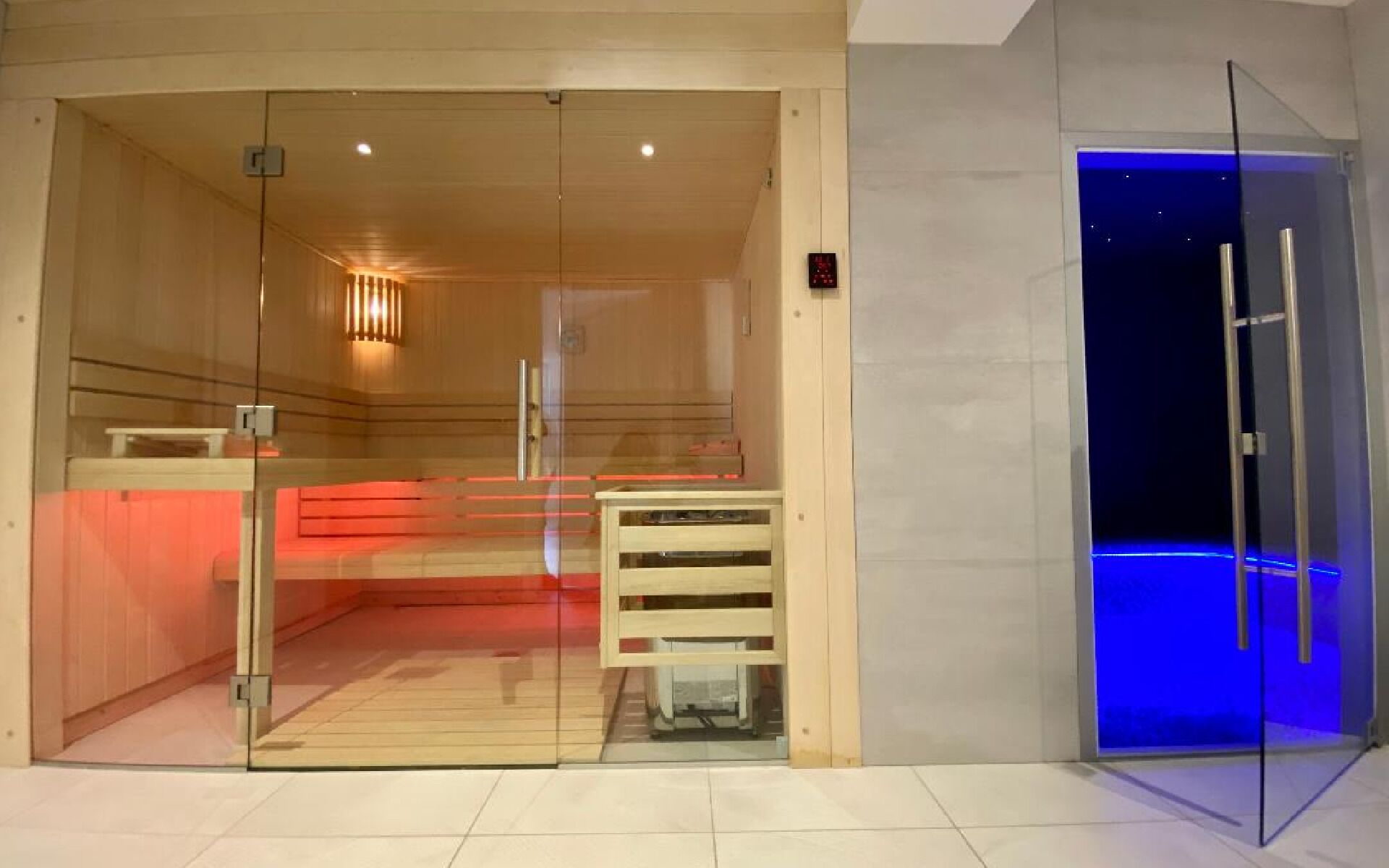 Een modern interieur met een glazen scheidingswand, een houten receptiebalie en een deur met blauwe verlichting.