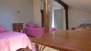 Quarto com duas camas, uma mesa de madeira e um guarda-roupa de madeira.