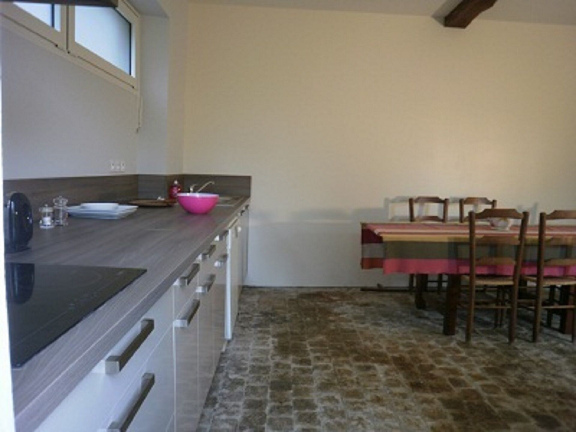 A kitchen with a stone floor, a wooden table, and a pink basin.