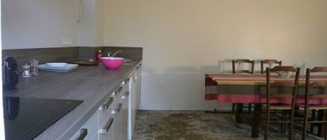 A kitchen with a stone floor, a wooden table, and a pink basin.