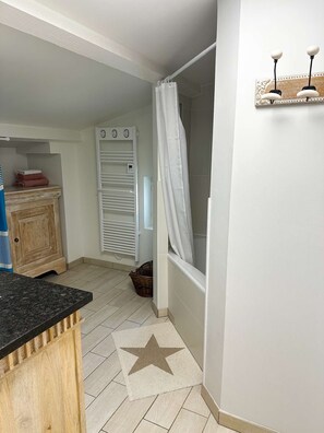 Une salle de bain avec une douche, un porte-serviettes et un meuble en bois.