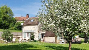 A stone house with a garden, a tree in bloom, and a clear blue sky. - Charming renovated farmhouse in Burgundy, near Vezelay. (Chamoux)
