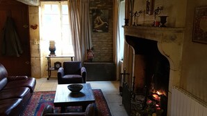 A cozy living room with a fireplace, leather sofa, and a stone wall. - Charming renovated farmhouse in Burgundy, near Vezelay. (Chamoux)