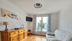 A cozy living room with a wooden cabinet, a television, and a sofa with patterned cushions. - Comfortable house, walk to beach and shops, pets allowed upon request (La Faute-sur-Mer)