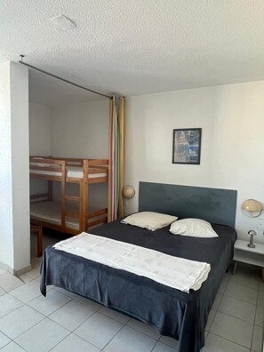 Una camera da letto con un letto a castello, un letto con due cuscini, una lampada fissata al muro e un quadro incorniciato.