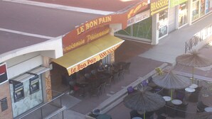 An outdoor café with tables and chairs, a sign for 'Le Bon Pain', and a storefront with 'BRASSERIE' visible. - Studio, 4px, great view of the marina, 66750 St Cyprien beach. 250 € week (Saint-Cyprien)