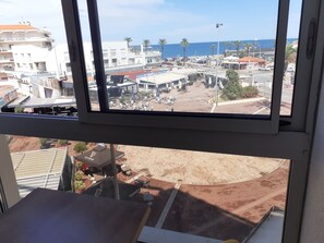 A view from a window overlooking a commercial area with buildings, outdoor seating, and a clear sky.