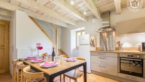 Una cocina moderna con una mesa de madera lista para comer, un extractor de acero inoxidable y un refrigerador blanco.
