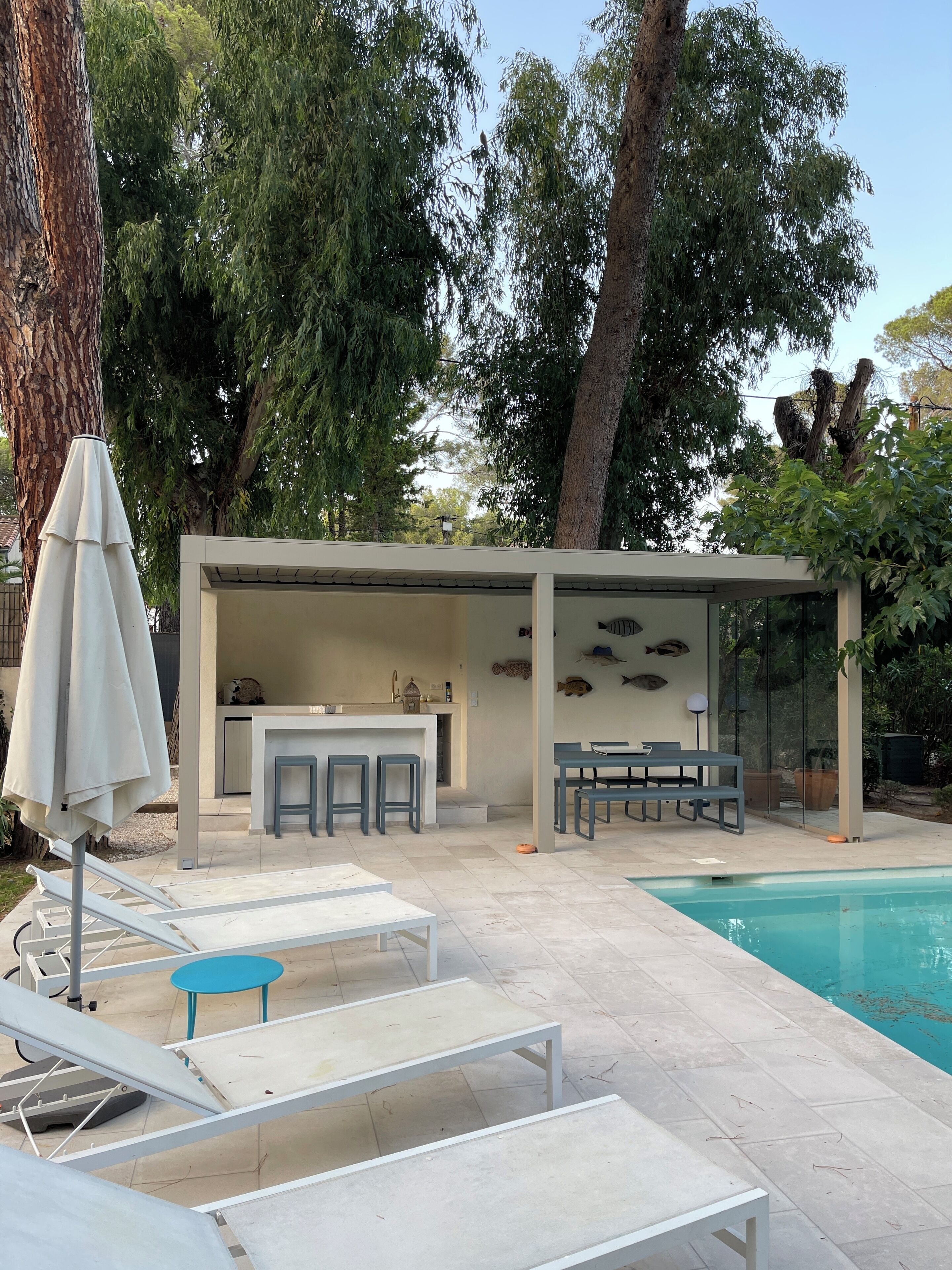 A modern outdoor pool area with lounge chairs, a bar, and a covered seating area.