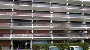 A multi-story building with balconies, a parking area, and a clear sky. - Stunning 3-room apartment on top floor in Chamrousse (Chamrousse)