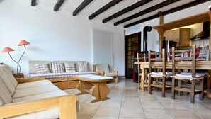 A cozy living room with a sofa, wooden chairs, a dining table, and a kitchen area with wooden furniture. - Stunning 3-room apartment on top floor in Chamrousse (Chamrousse)