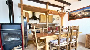 A dining area with a wooden table and chairs, a built-in oven, and a kitchen in the background. - Stunning 3-room apartment on top floor in Chamrousse (Chamrousse)