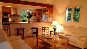 A cozy living room with a sofa, a coffee table, and a kitchen area with a bar. - Villa with swimming pool and private park 5000m2, 3 bedrooms 3 bathrooms, Bonifacio/Porto-Vecchio (Bonifacio)