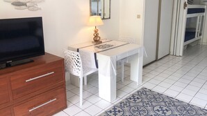 A hotel room with a TV, a dining table with chairs, a lamp, a mirror, and a bed. - Homerez - Sea View Studio - Collioure (Collioure)