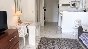 A modern kitchen with white cabinets, a microwave, and a small dining area with a table and chairs. - Homerez - Sea View Studio - Collioure (Collioure)