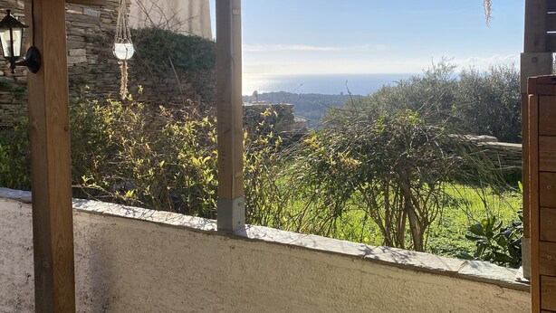 A covered outdoor area with a view of a green landscape and distant hills.