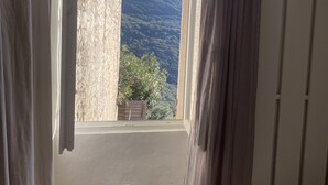 A room with a window overlooking a mountainous landscape.