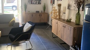 A modern living room with a black chair, wooden cabinets, and a tiled floor.