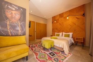 A bedroom with a bed, a yellow chair, a colorful rug, and a wooden wall panel.