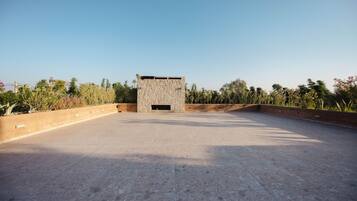 Een open terras met een stenen constructie, omgeven door beplanting.